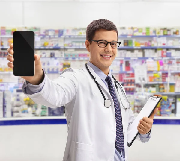 Mladý Phamrasist Uvnitř Lékárny Ukazuje Smartphone Usmívá — Stock fotografie