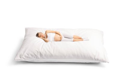 Beyaz arka planda büyük bir yastıkta uyuyan pijamalı hamile bir kadın.