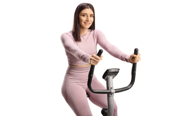 若いですフィット女性でスポーツウェアに乗って固定自転車と笑顔でカメラで隔離された白い背景 — ストック写真