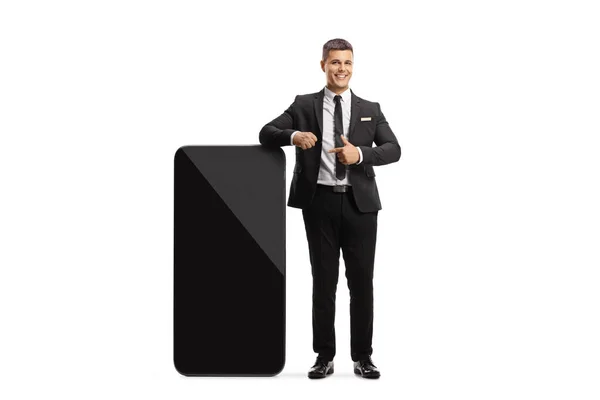 スーツの男とタイは大きな携帯電話にもたれて白い背景に隔離されたポインティング — ストック写真