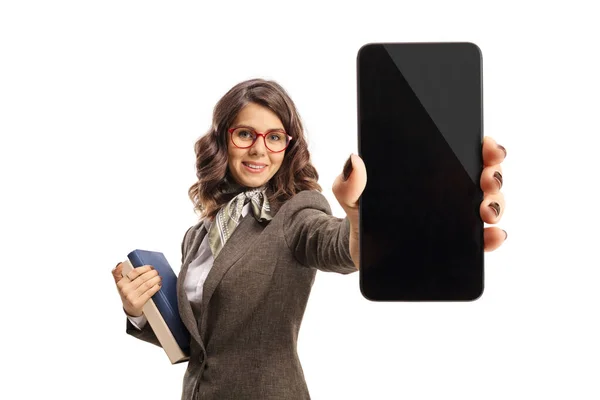 年轻女性拿着书本 在白色背景的相机前展示智能手机 — 图库照片