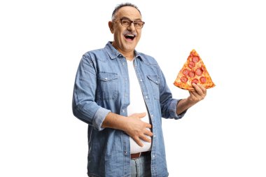 Pepperonili pizzayla neşeli olgun bir adam karnını tutuyor ve beyaz arka planda izole bir şekilde gülümsüyor.