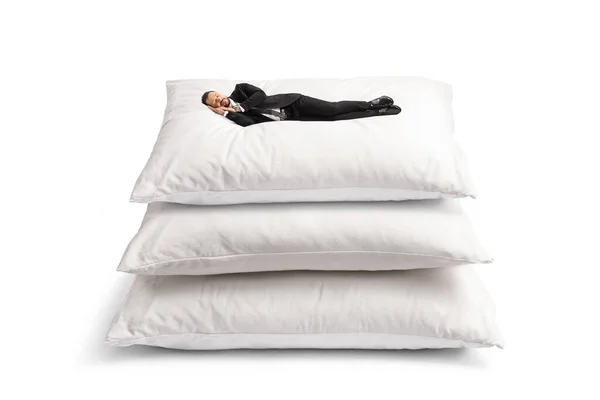 穿着西装 睡在一堆白色背景的大枕头上的商人 — 图库照片