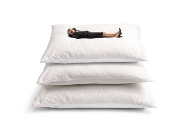 Beyaz arka planda izole edilmiş büyük yastıkların üzerinde yatan iş kadını.