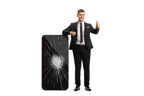 Professional Man Leaning Big Smartphone Broken Screen Gesturing Thumbs Isolated — 스톡 사진