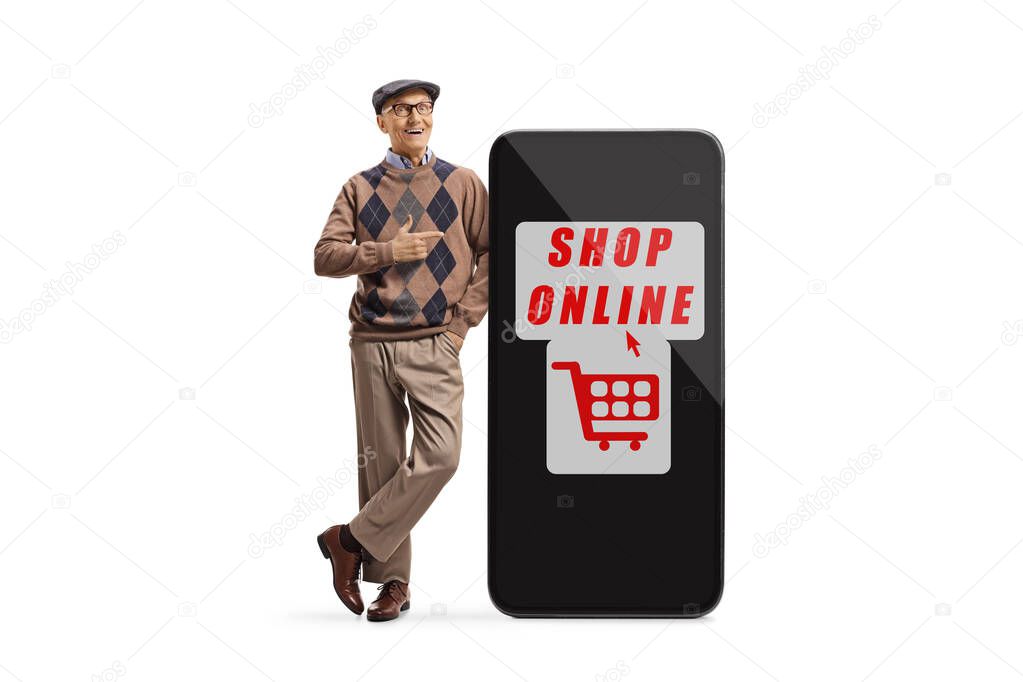 Full length portrait of a senior man smiling and pointing to a big smartphone with text shop online isolated on white background