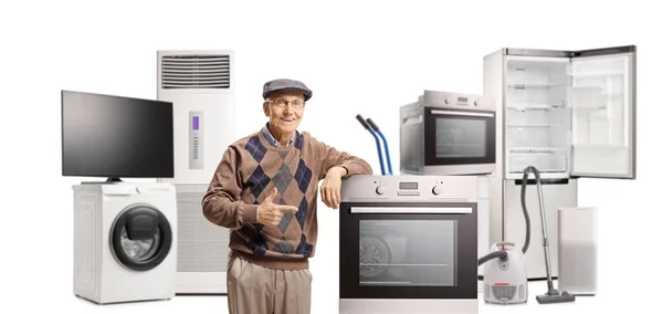 老人拿着家用电器站在那里 指着电炉 用白色背景隔开 — 图库照片