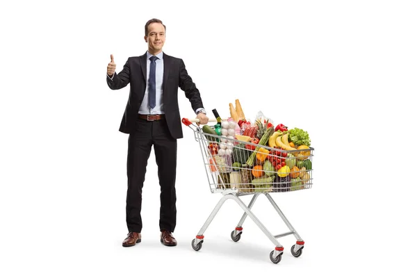 一个商人的全长肖像 他站在购物车里 手里拿着食物 用白色背景把他的大拇指做着手势 — 图库照片
