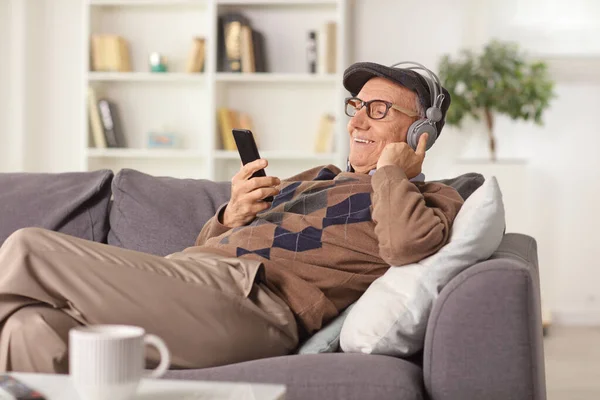 Рекламированный Пожилой Человек Сидит Дома Диване Слушает Музыку Смартфона — стоковое фото