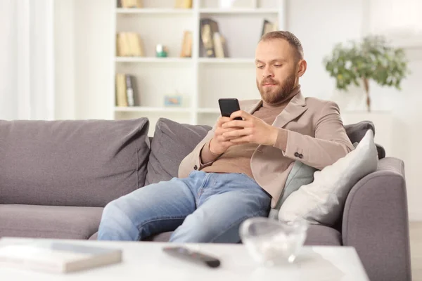 Jovem Sentado Sofá Casa Usando Smartphone — Fotografia de Stock