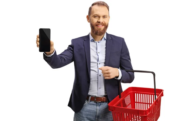 Smiling Young Man Holding Empty Shopping Basket Showing Mobile Phone — ストック写真