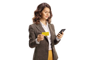 Smrtphone kullanan ve beyaz arka planda izole edilmiş bir kredi kartı tutan genç bir kadın.