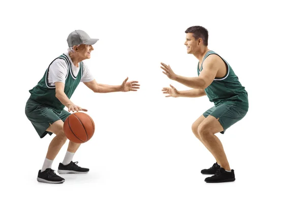 フル長さプロファイルショットの若いですと高齢者の男で緑のジャージ遊びバスケットボール孤立した上に白の背景 — ストック写真