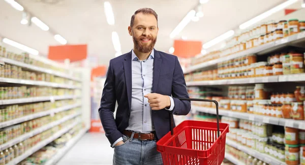 Smiling Young Man Holding Empty Shopping Basket Posing Supermarket — Fotografia de Stock