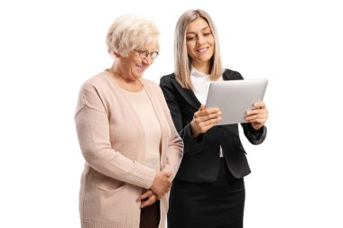 İş kadını dijital tablet gösteriyor ve beyaz arka planda izole edilmiş yaşlı bir kadınla duruyor.