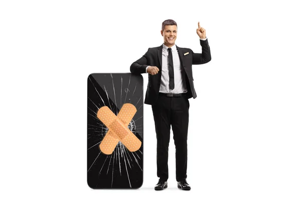 Businessman Standing Pointing Next Smartphone Broken Screen Bandage Isolated White — Fotografia de Stock