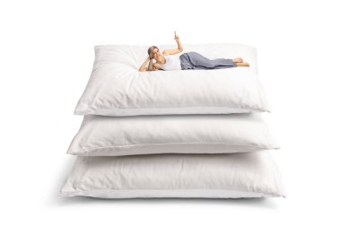 Genç bir kadın, rahat bir yastık yığınının üzerinde uzanıyor ve beyaz arka planda izole edilmiş bir şekilde yukarı bakıyor.