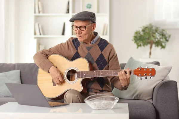 Starszy Mężczyzna Gra Gitarze Akustycznej Siedzi Przed Laptopem Domu — Zdjęcie stockowe