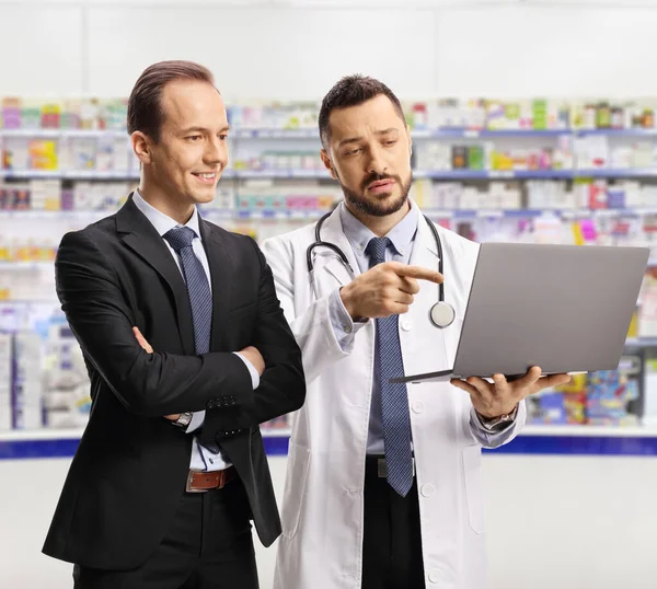 Male Pharmacist Showing Laptop Screen Businessman Pharmacy Store — Zdjęcie stockowe