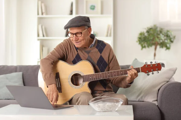 Akustik Gitarlı Yaşlı Bir Adam Evdeki Dizüstü Bilgisayarla Kanepede Oturuyor — Stok fotoğraf