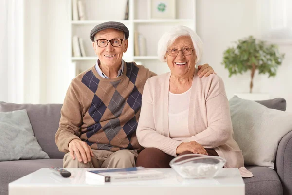 Feliz Casal Idoso Sentado Sofá Casa Sorrindo Para Câmera — Fotografia de Stock