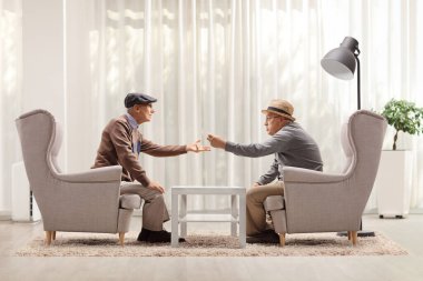 Üst düzey adamlar koltuklarda oturup bir odada tartışıyorlar.