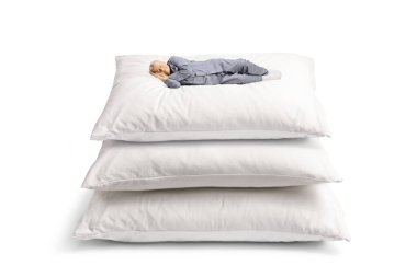 Beyaz arka planda izole edilmiş yastık yığınının üzerinde uyuyan pijamalı yaşlı bir adam.