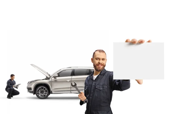 車のサービスと白い背景に隔離された空白の段ボールを示す整備士 — ストック写真