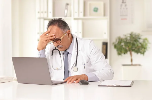 Doctor Cansado Sentado Una Oficina Frente Una Computadora Portátil Sosteniendo — Foto de Stock