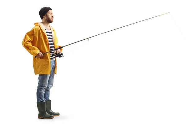 一个穿着雨衣的渔夫站在一个白色背景的钓竿上拍摄的全长轮廓 — 图库照片