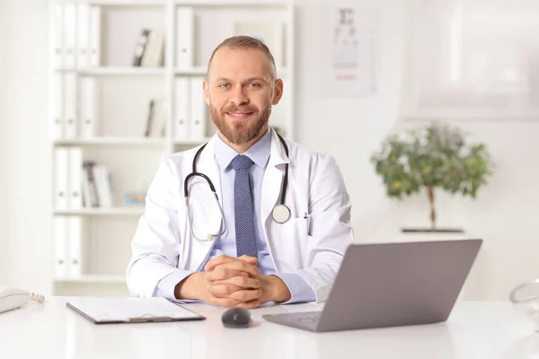 Joven Médico Masculino Sentado Una Oficina Sonriendo Cámara —  Fotos de Stock