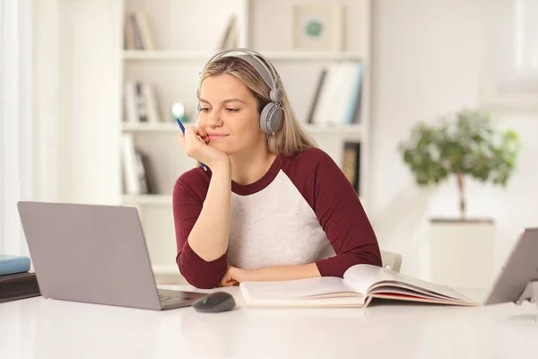 ノートパソコンの前でヘッドフォンで勉強する女子学生 — ストック写真