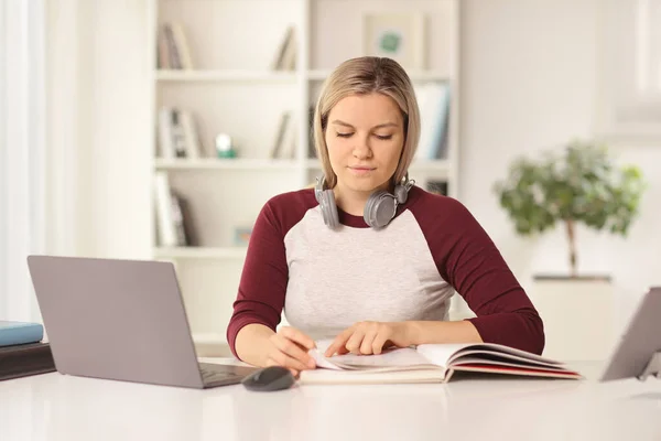 ラップトップコンピュータの前で勉強し 自宅で本を読む女性学生 — ストック写真