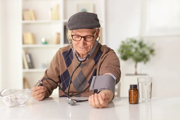 Evde Kan Basıncını Ölçen Yaşlı Bir Adam Masada Şişedeki Haplarla — Stok fotoğraf