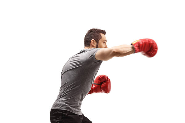 Profile shot of a young man punching with boxing gloves isolated on white background