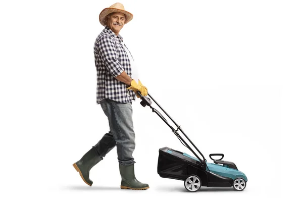 白い背景に隔離された芝刈り機を使用して わらの帽子とブーツを持つ成熟した男の完全な長さのプロフィールショット — ストック写真
