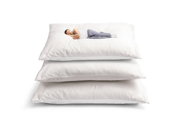 穿着睡衣的年轻人睡在一堆白色背景的软垫上 — 图库照片