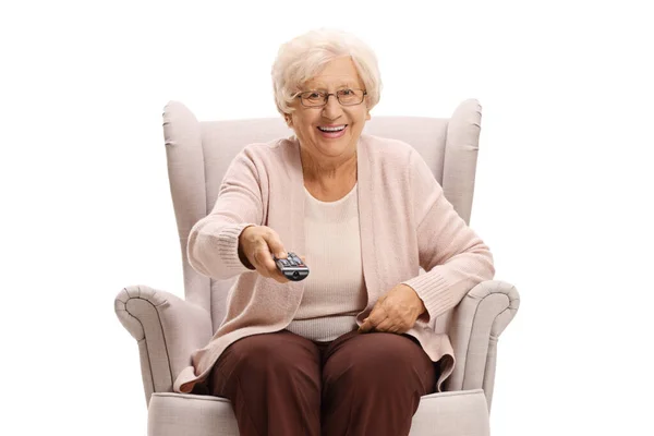 Oudere Vrouw Zit Een Fauteuil Houdt Een Afstandsbediening Geïsoleerd Witte — Stockfoto