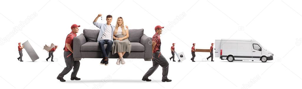 Workers from a removal company carrying a young couple sitting on a gray sofa and holding a house key isolated on white background