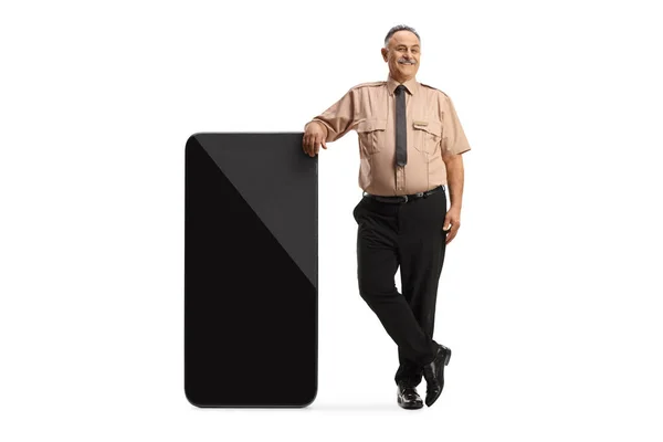 Beveiligingsagent Leunend Een Grote Mobiele Telefoon Wijzend Geïsoleerd Witte Achtergrond — Stockfoto