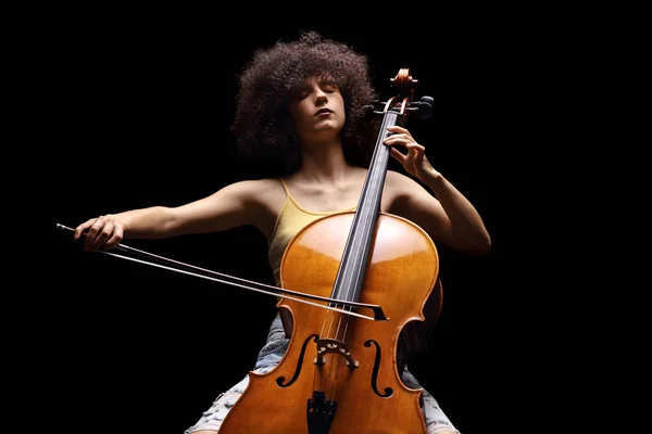 在黑人背景下独立演奏大提琴的女艺术家 — 图库照片