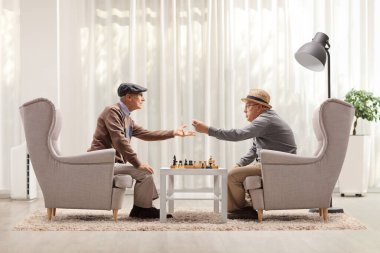 Son sınıflar koltuklarda oturmuş satranç oynuyor ve bir odada tartışıyorlar.