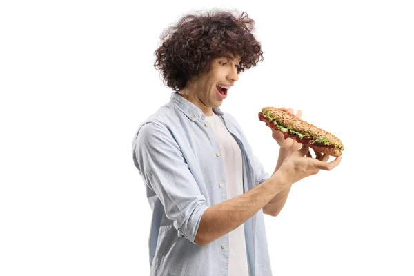 Junger Mann Mit Lockigem Haar Hält Ein Baguette Sandwich Auf — Stockfoto