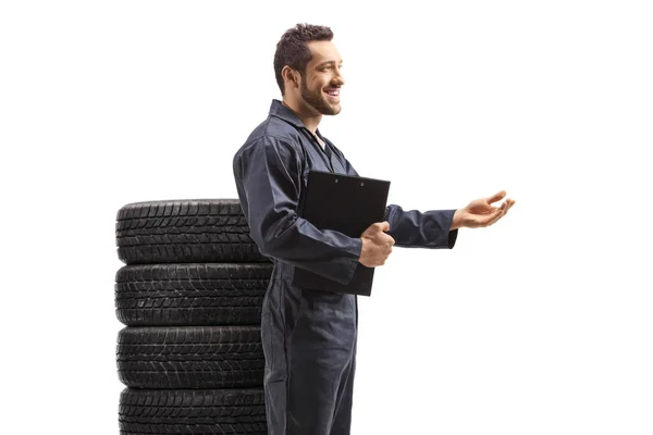 带一堆轮胎的汽车修理工用手隔离在白色背景上解释 — 图库照片