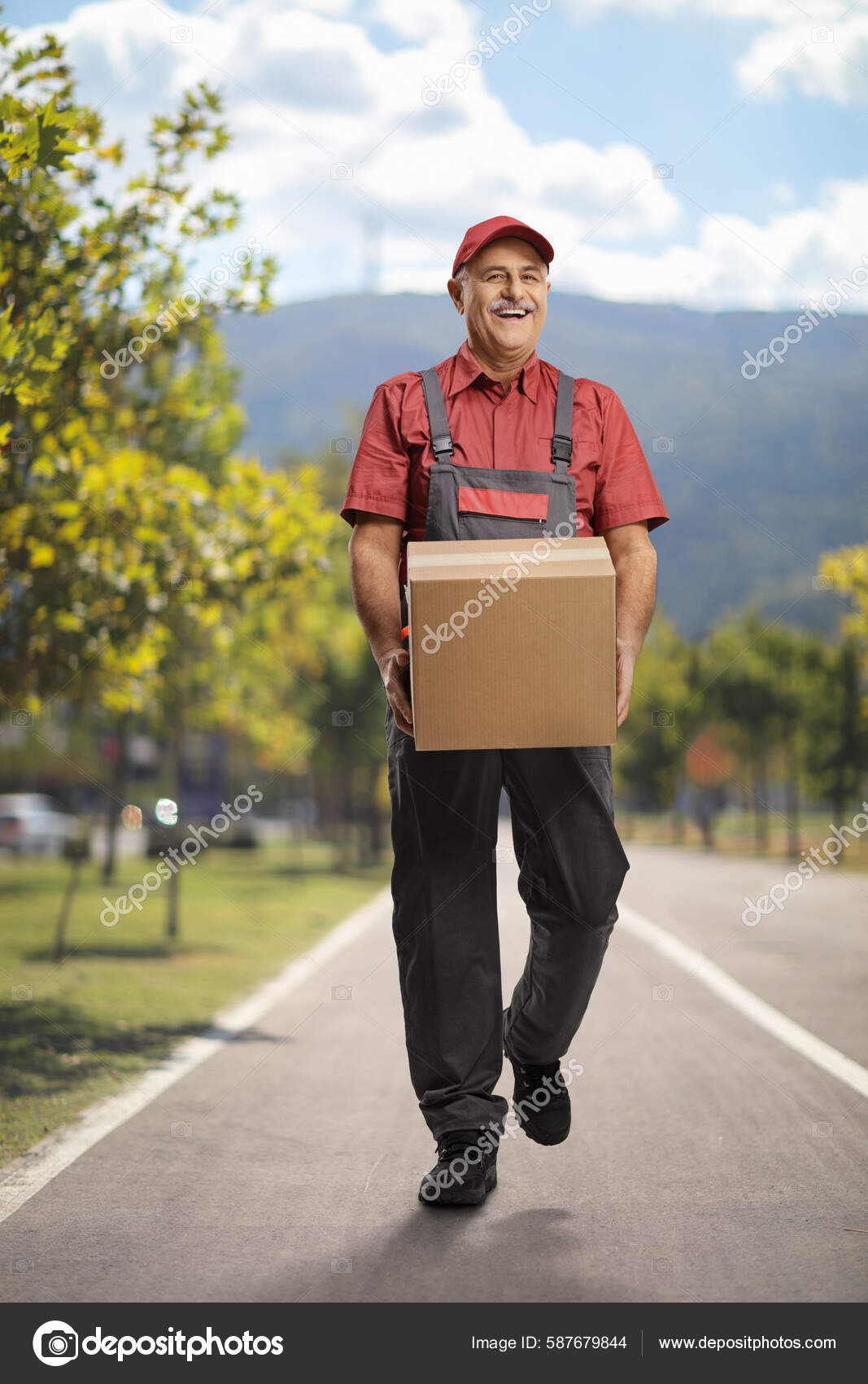 Mature Delivery Man Walking Outdoors Carrying Cardboard Box Stock Photo Mature Delivery Man Walking Outdoors Carrying Cardboard Box Stock Photo