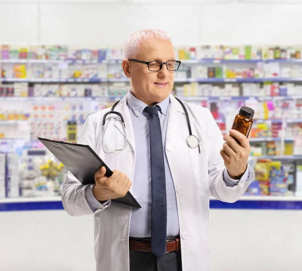Pharmacist Looking Bottle Pills Holding Clipboard Chemist Store — Fotografia de Stock