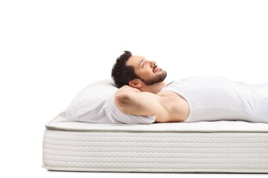 Young man in a white vest lying on a mattress isolated on white background