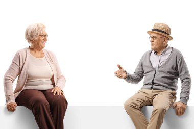 Üst düzey erkek ve kadın bir panelde oturup beyaz arka planda izole edilmiş bir şekilde sohbet ediyorlar.