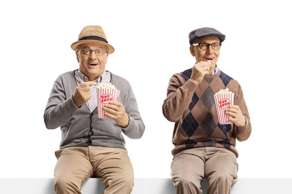Пожилые Мужчины Сидящие Стене Едят Попкорн Улыбаются Камеру Белом Фоне — стоковое фото
