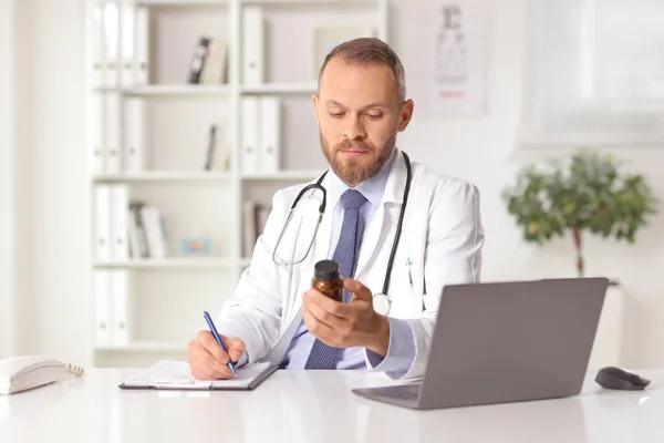 Young Male Doctor Sitting Office Holding Bottle Pills Writing Document — Fotografia de Stock